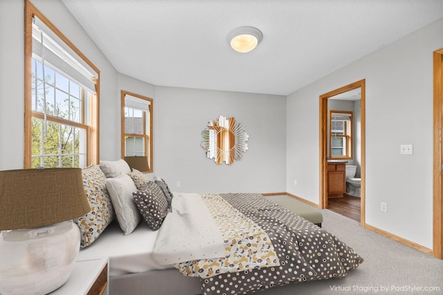 carpeted bedroom featuring ensuite bath and baseboards