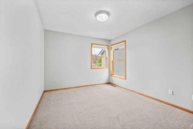 spare room featuring a textured ceiling, baseboards, visible vents, and carpet