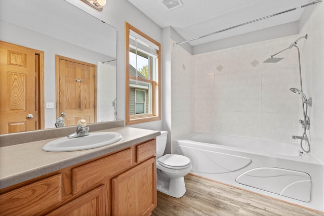 full bath with toilet, shower / bath combination, wood finished floors, and vanity