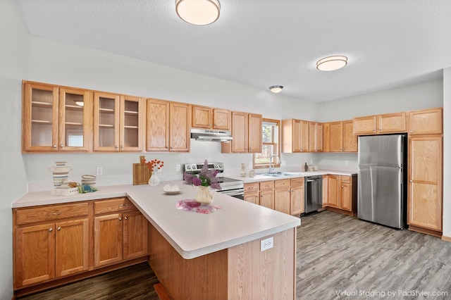 kitchen with stainless steel appliances, under cabinet range hood, a peninsula, light countertops, and a textured ceiling