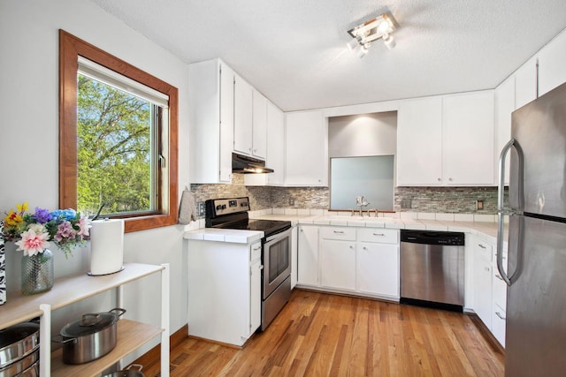3664 Abbey Way Unit C, Eagan, MN 55123 - kitchen with appliances with stainless steel finishes, a sink, tile counters, under cabinet range hood, and decorative backsplash