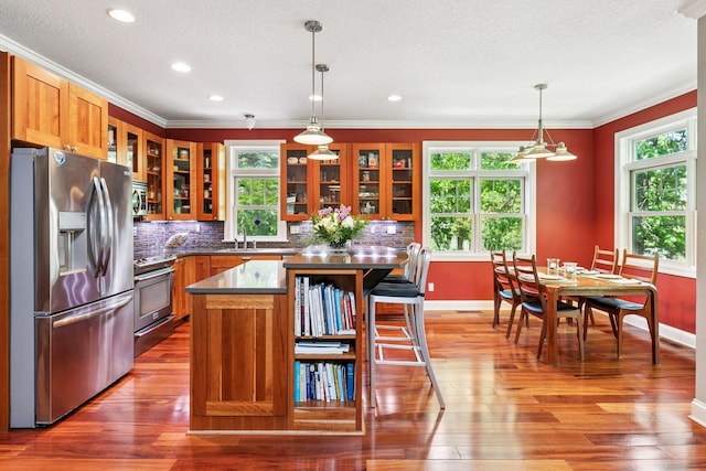 16710 Edgewood Ave, Wayzata, MN 55391 - kitchen with appliances with stainless steel finishes, brown cabinetry, healthy amount of natural light, wood finished floors, and crown molding