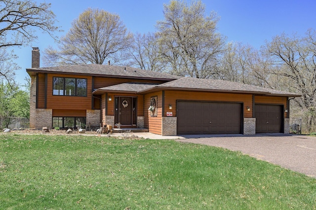 view of front facade with brick siding, a garage, a front lawn, and a chimney