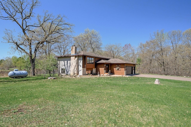 view of front facade with concrete driveway, a chimney, a front yard, and an attached garage