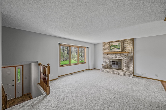 unfurnished living room with carpet, a textured ceiling, baseboards, and a brick fireplace