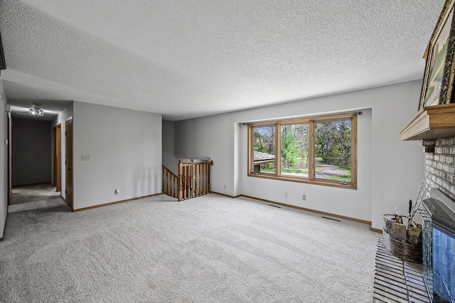 unfurnished living room featuring carpet, a textured ceiling, visible vents, and a fireplace