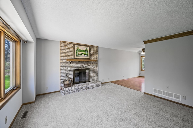 unfurnished living room with carpet flooring, a textured ceiling, visible vents, and a fireplace