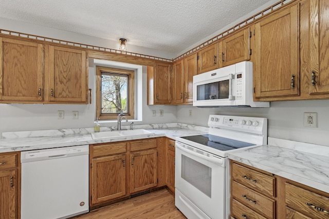 kitchen with light countertops, brown cabinetry, a sink, and white appliances