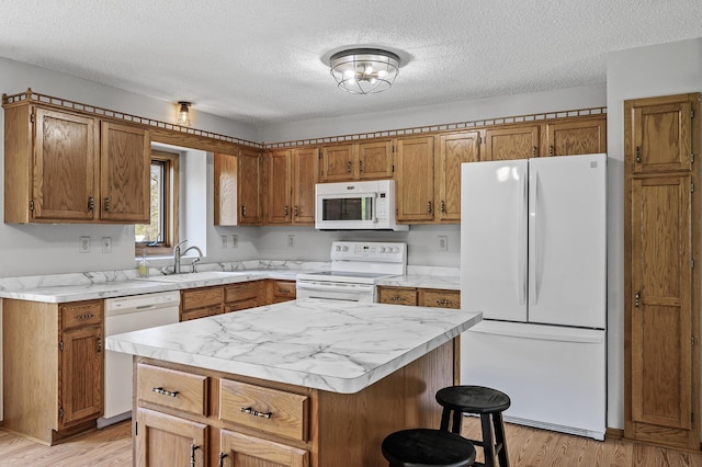 kitchen with a textured ceiling, brown cabinetry, white appliances, a sink, and light countertops