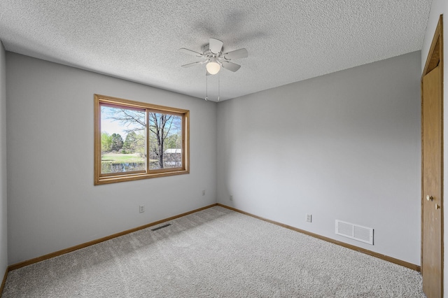 carpeted empty room with a ceiling fan, baseboards, visible vents, and a textured ceiling