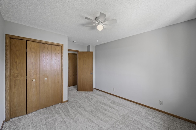 unfurnished bedroom featuring carpet, a textured ceiling, a closet, and baseboards