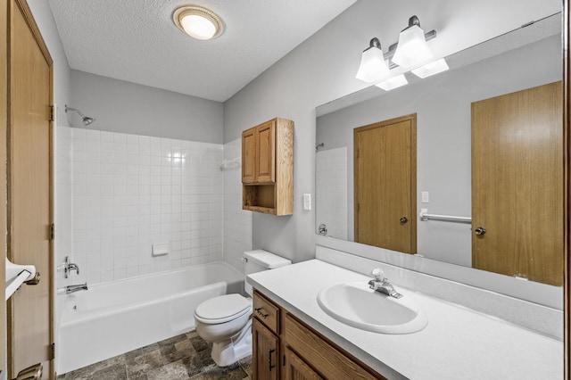 bathroom featuring toilet, vanity, a textured ceiling, stone finish flooring, and tub / shower combination
