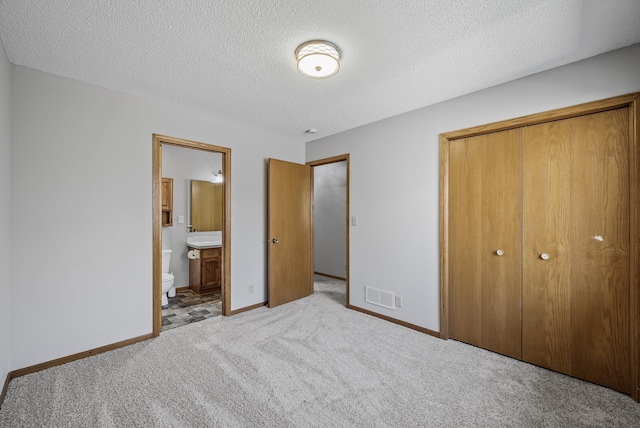 bedroom with a closet, a textured ceiling, baseboards, visible vents, and light carpet