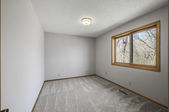 spare room featuring baseboards, a textured ceiling, visible vents, and carpet
