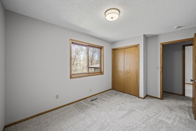 unfurnished bedroom with a closet, a textured ceiling, baseboards, carpet flooring, and visible vents