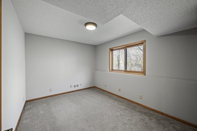 spare room with a textured ceiling, visible vents, baseboards, and carpet floors