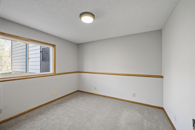 carpeted spare room with baseboards and a textured ceiling