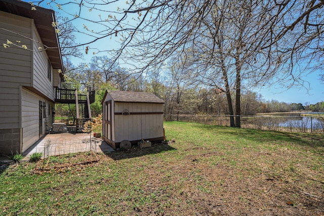 view of yard with an outdoor structure, fence, a storage unit, a patio, and a water view