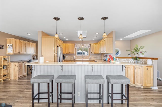 15344 Blackhawk Rd, Lake Eunice Twp, MN 56511 - kitchen featuring a peninsula, light brown cabinets, freestanding refrigerator, a skylight, and light wood finished floors