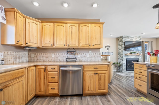15344 Blackhawk Rd, Lake Eunice Twp, MN 56511 - kitchen featuring appliances with stainless steel finishes, decorative backsplash, a stone fireplace, wood finished floors, and light brown cabinets