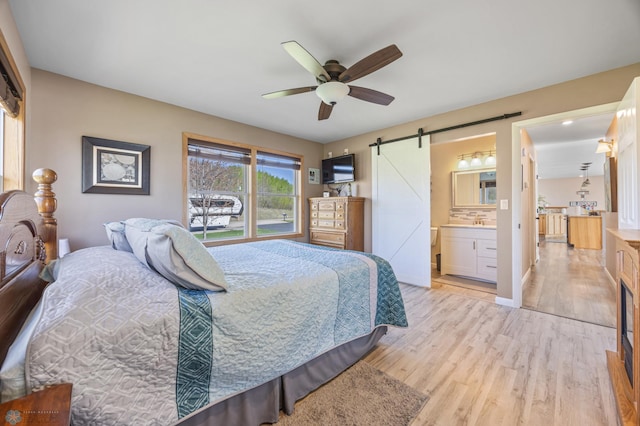15344 Blackhawk Rd, Lake Eunice Twp, MN 56511 - bedroom featuring a barn door, light wood finished floors, ceiling fan, baseboards, and connected bathroom