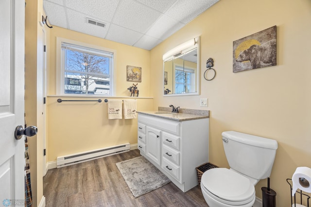 15344 Blackhawk Rd, Lake Eunice Twp, MN 56511 - bathroom featuring a baseboard radiator, a paneled ceiling, wood finished floors, toilet, and vanity