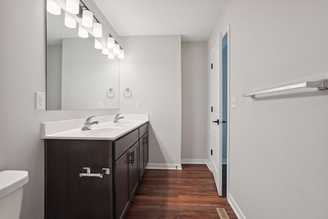 2219 Youngman Ave, Saint Paul, MN 55116 - bathroom featuring double vanity, toilet, wood finished floors, and a sink