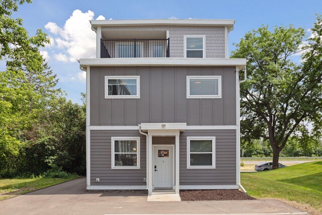 2219 Youngman Ave, Saint Paul, MN 55116 - view of front of house featuring board and batten siding, a front lawn, and a balcony