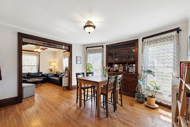 dining area featuring baseboards, a ceiling fan, and light wood-style floors