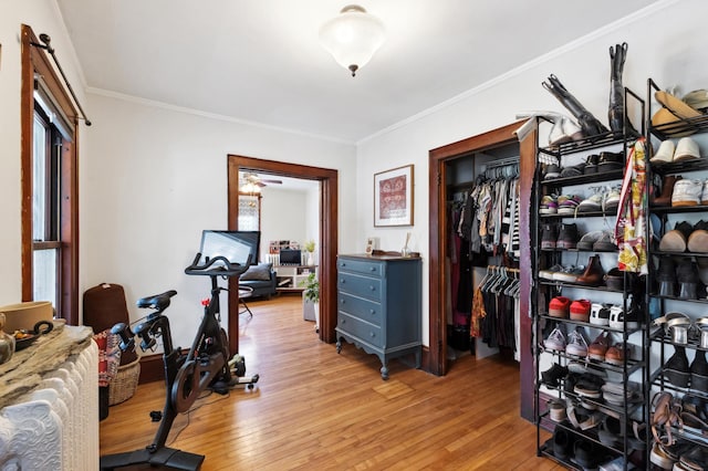 exercise room with crown molding and light wood-style flooring