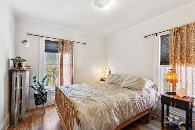 bedroom featuring crown molding, hardwood / wood-style flooring, and radiator heating unit