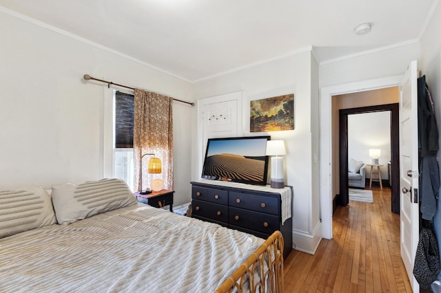 bedroom with baseboards, ornamental molding, and hardwood / wood-style flooring