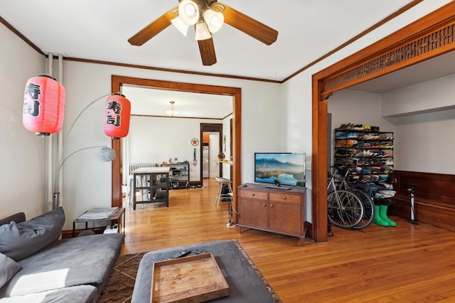 living room featuring wood finished floors, a ceiling fan, and ornamental molding