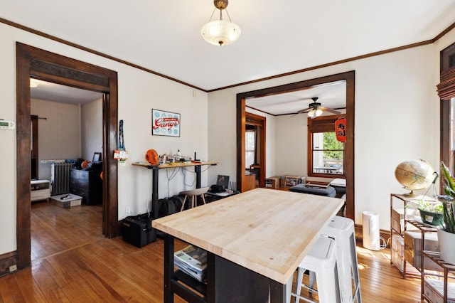dining area with crown molding, wood-type flooring, baseboards, and ceiling fan