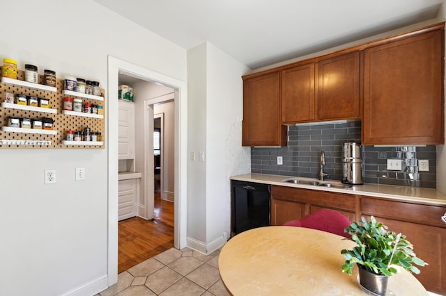 kitchen featuring a sink, brown cabinetry, dishwasher, decorative backsplash, and light countertops