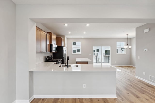 6742 Wildflower Way, Minnetrista, MN 55331 - kitchen featuring gas range, a peninsula, light countertops, a chandelier, and light wood-style flooring