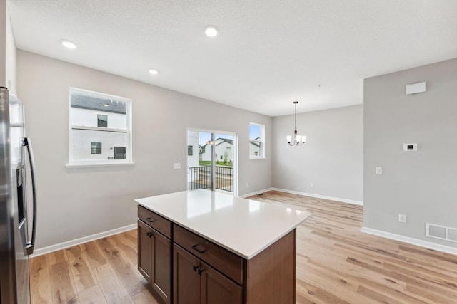 6742 Wildflower Way, Minnetrista, MN 55331 - kitchen with stainless steel fridge, light wood-style flooring, a chandelier, hanging light fixtures, and light countertops