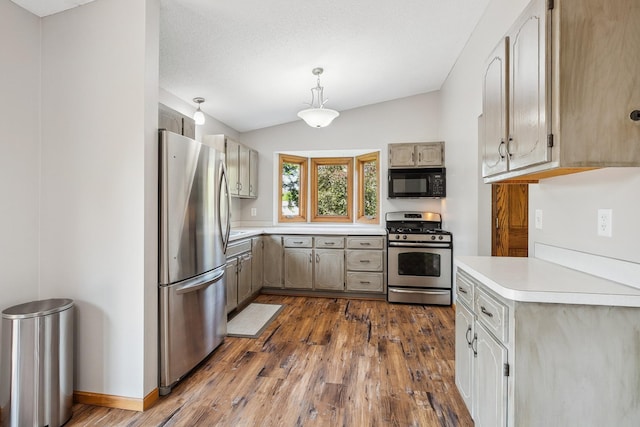 6913 Sumac Ct, Centerville, MN 55038 - kitchen with appliances with stainless steel finishes, light countertops, vaulted ceiling, dark wood-style flooring, and hanging light fixtures
