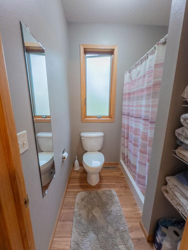 bathroom featuring toilet, wood finished floors, a textured ceiling, and a shower with curtain