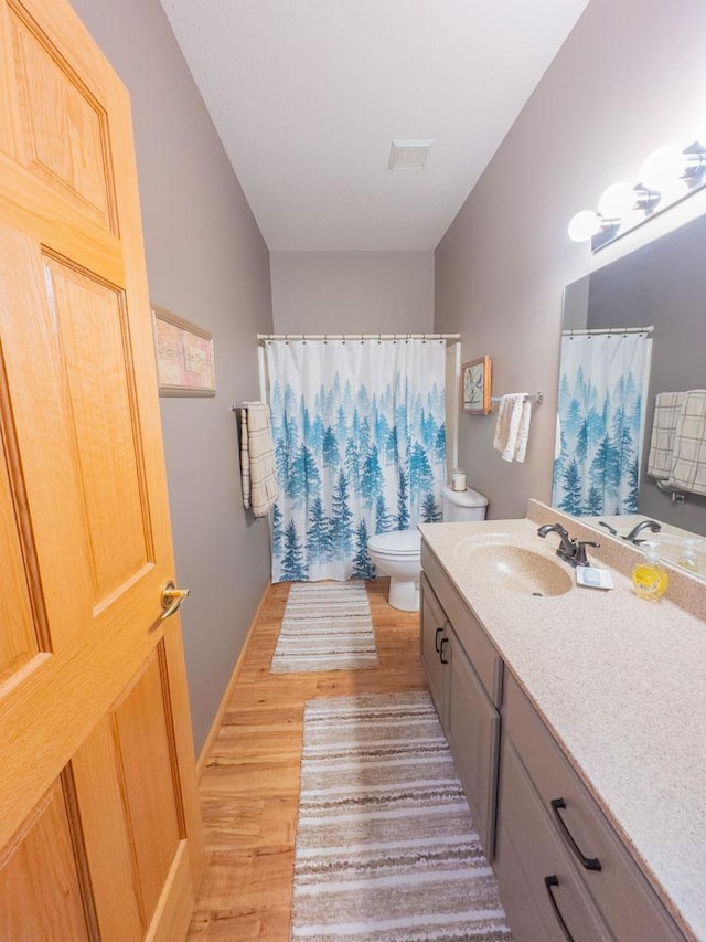 bathroom with wood finished floors, toilet, vanity, and a shower with curtain