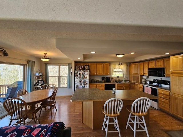 19319 Elsie Way NW, Bemidji, MN 56601 - kitchen featuring a textured ceiling, a kitchen island, black appliances, dark countertops, and wood finished floors