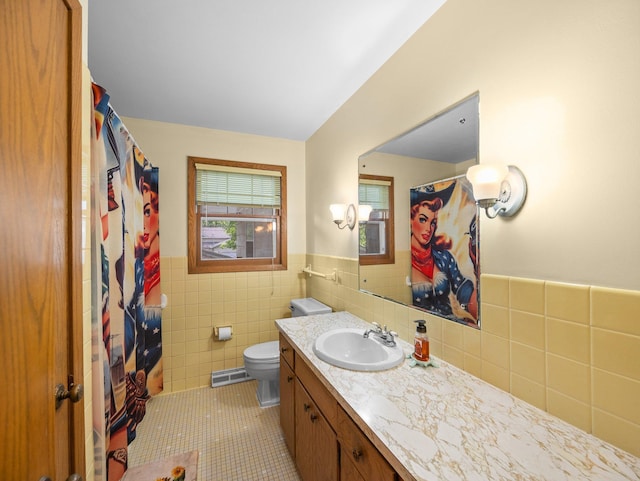 1716 9th Ave SE, Saint Cloud, MN 56304 - bathroom featuring tile walls, vanity, wainscoting, tile patterned floors, and toilet
