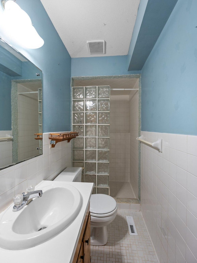 1716 9th Ave SE, Saint Cloud, MN 56304 - full bath featuring tile walls, a tile shower, vanity, toilet, and tile patterned floors