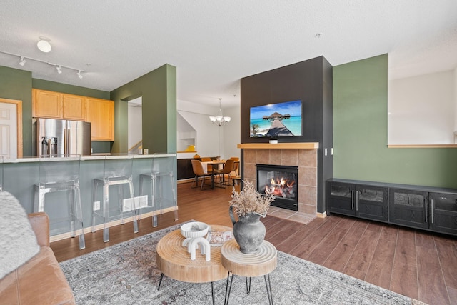 living area with a textured ceiling, a chandelier, wood finished floors, and baseboards