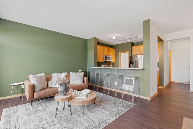 living room featuring rail lighting, wood finished floors, and baseboards