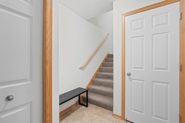 stairs featuring a textured ceiling and baseboards