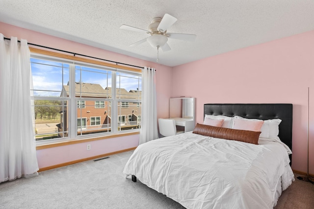 bedroom featuring a ceiling fan, a textured ceiling, baseboards, carpet flooring, and visible vents