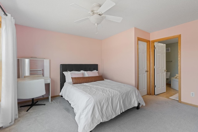 carpeted bedroom featuring baseboards, ensuite bath, visible vents, and a ceiling fan