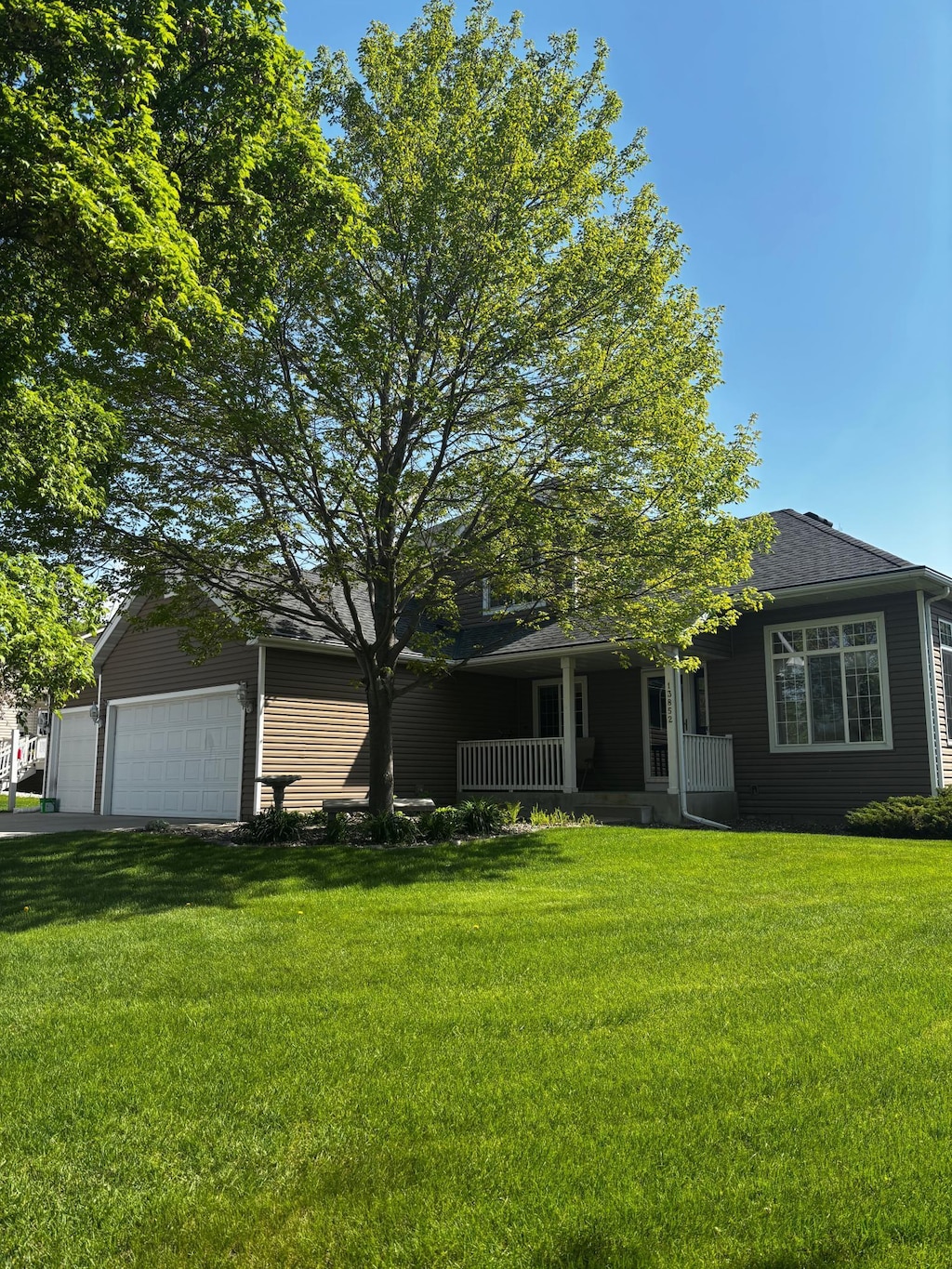 13852 Jasmine Way, Rogers, MN 55374 - view of front of home with a front yard, an attached garage, covered porch, and a shingled roof