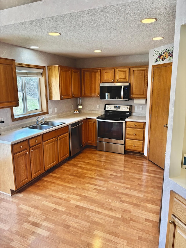 13852 Jasmine Way, Rogers, MN 55374 - kitchen with stainless steel appliances, a sink, light wood-type flooring, light countertops, and a textured ceiling